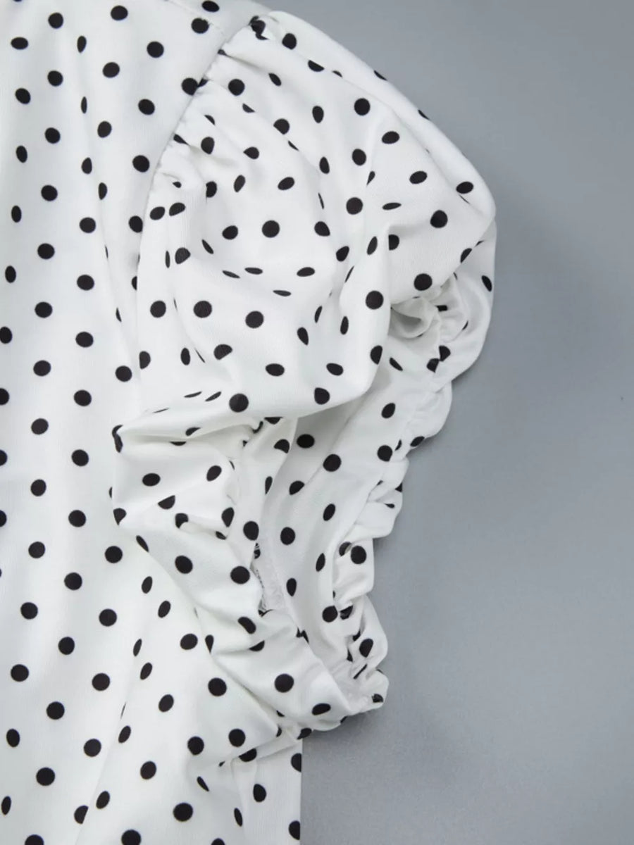 White t-shirt with black polka dots and ruched sleeve detail.