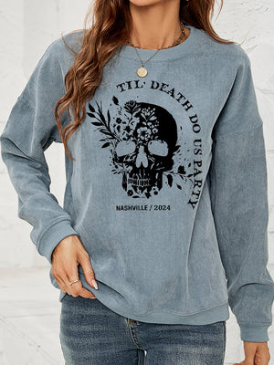 French blue corduroy sweatshirt with floral skull graphic and text.