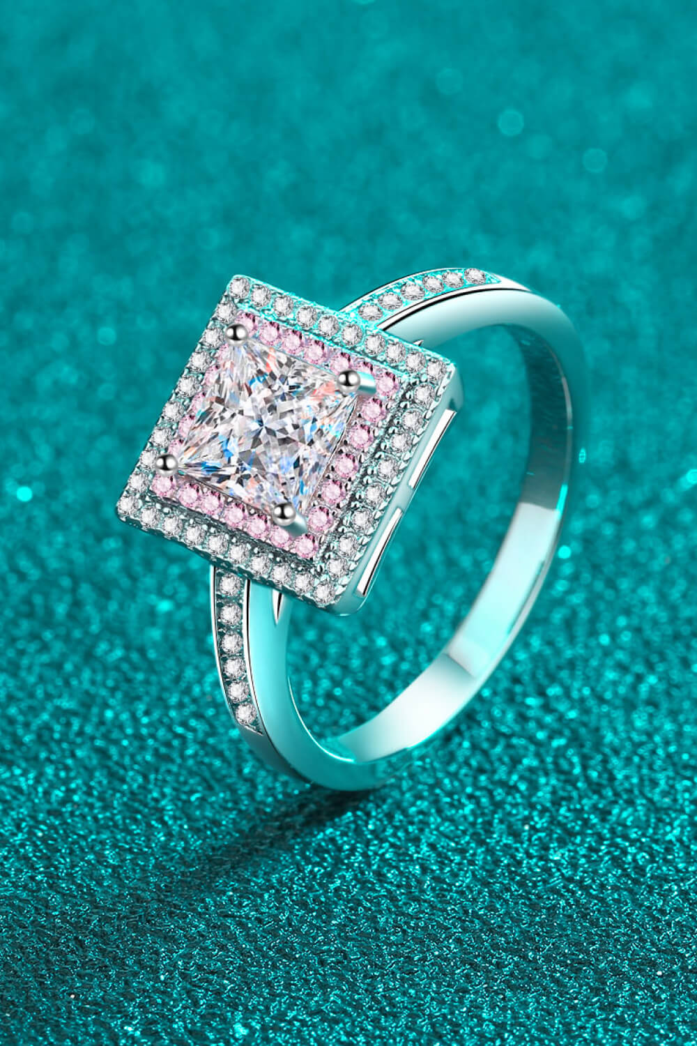 Silver princess cut halo ring with pink accents and a large center stone.