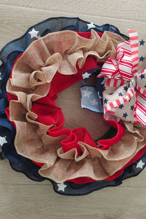 Patriotic ruffled burlap wreath with red, white, and blue stars and stripes bow.