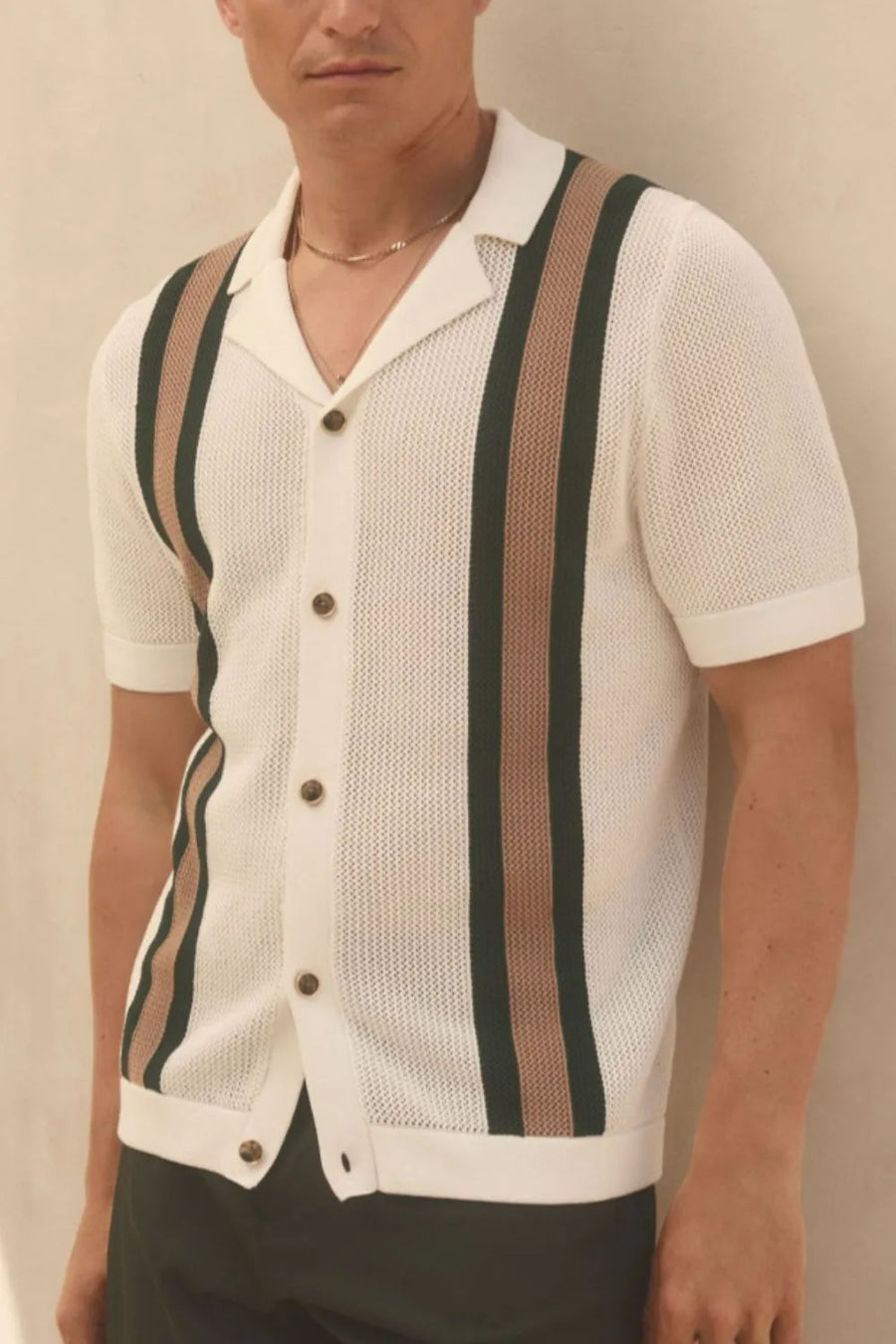 Ivory knit polo shirt with vertical stripe detail and button front.