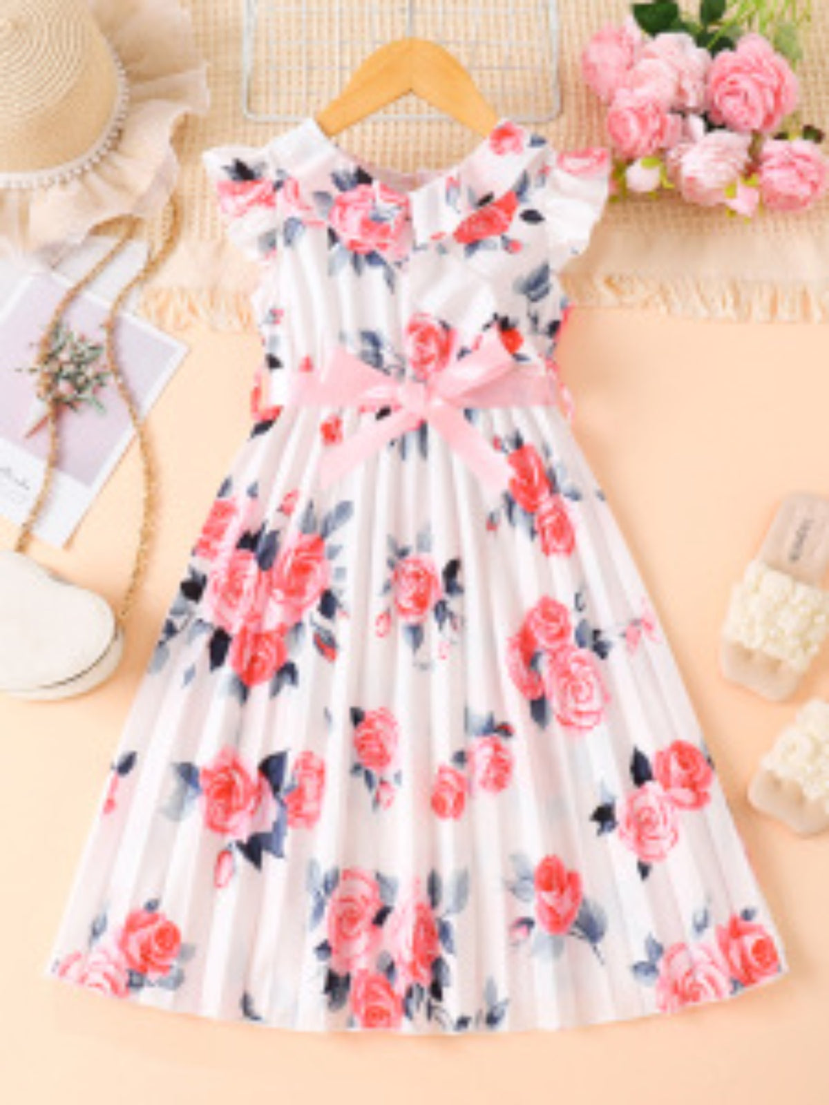 Toddler floral print dress with ruffle cap sleeves, pink bow, and pleated skirt.