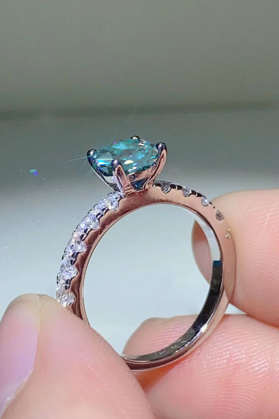 Celestial teal moissanite ring with pavé band, sky blue gemstone.