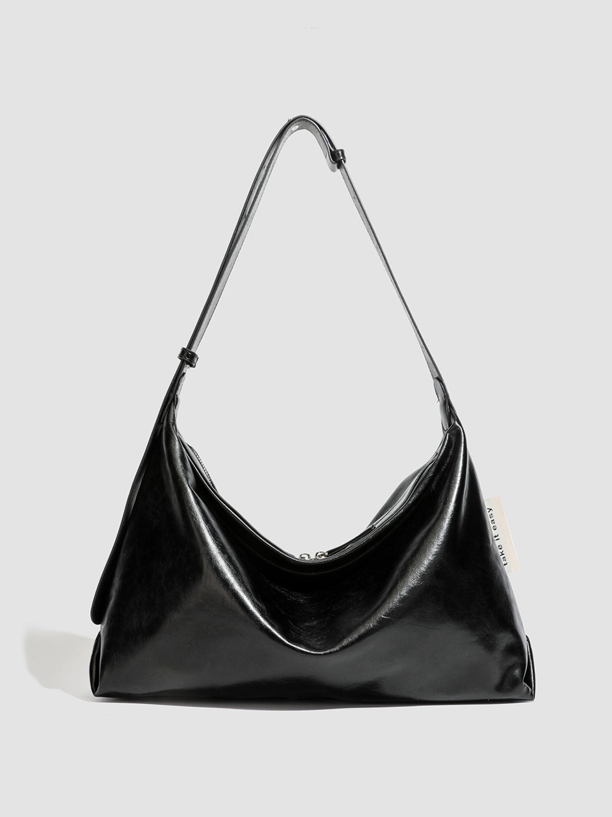 shoulder bag in black featuring glossy finish and slouchy fit