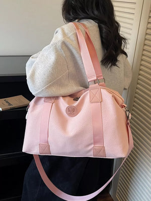 Pink perforated duffle bag with dual handles and a crossbody strap, perfect for gym or travel.