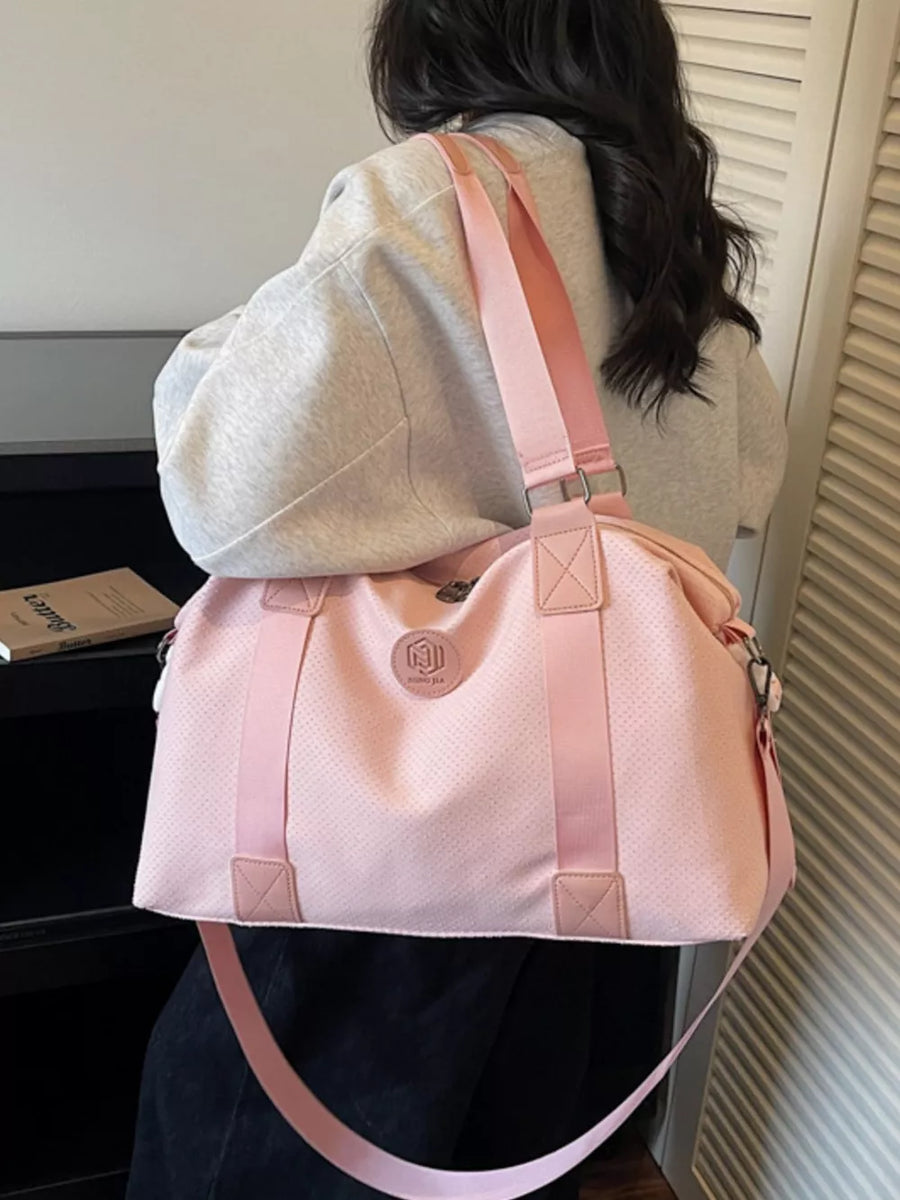 Pink perforated duffle bag with dual handles and a crossbody strap, perfect for gym or travel.