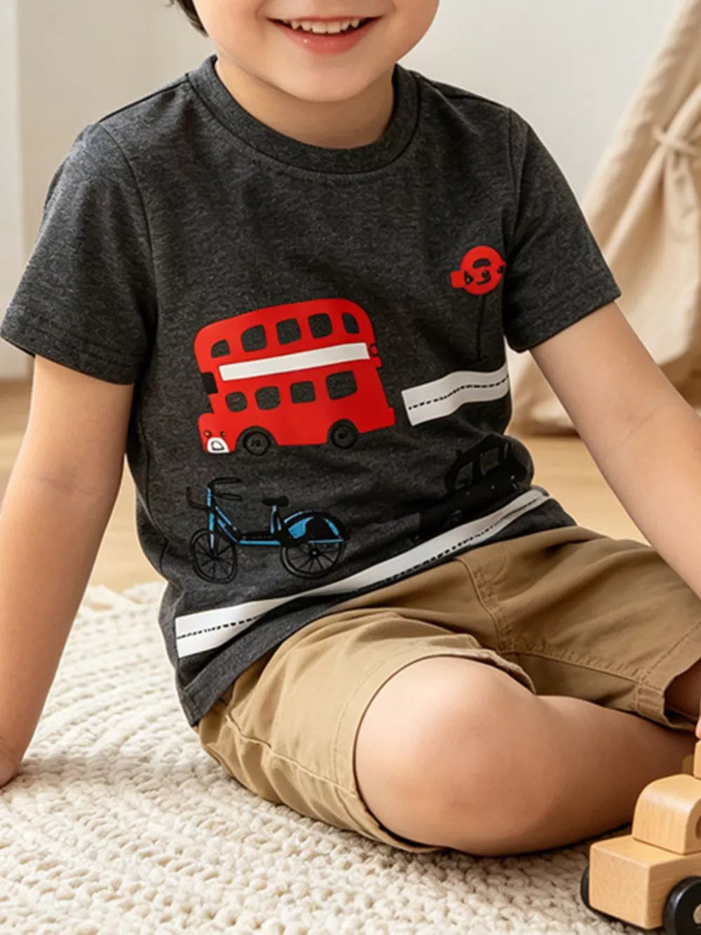 Kids' dark grey cotton t-shirt with red double-decker bus and blue bicycle graphic.
