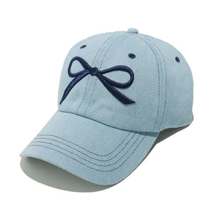 Light blue denim baseball cap with embroidered navy bow detail.