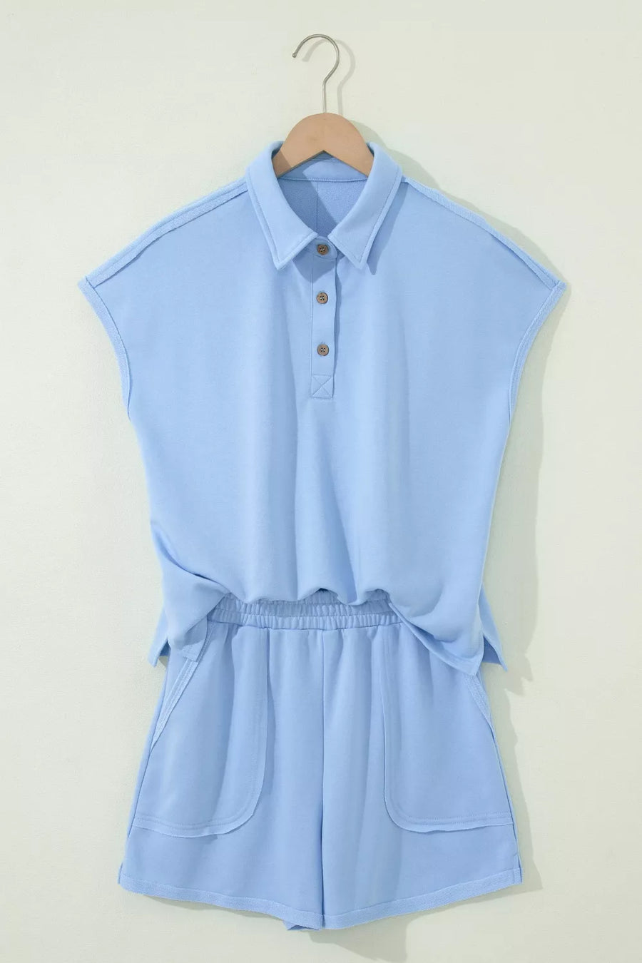 Light blue sleeveless polo shirt and shorts set with button detail and pockets.