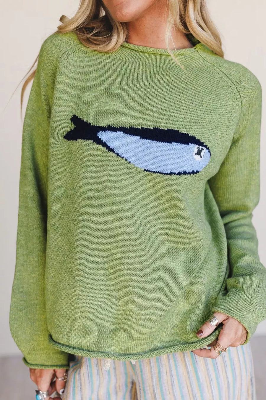 Green knit sweater with a blue and black fish graphic, crew neck, long sleeves.