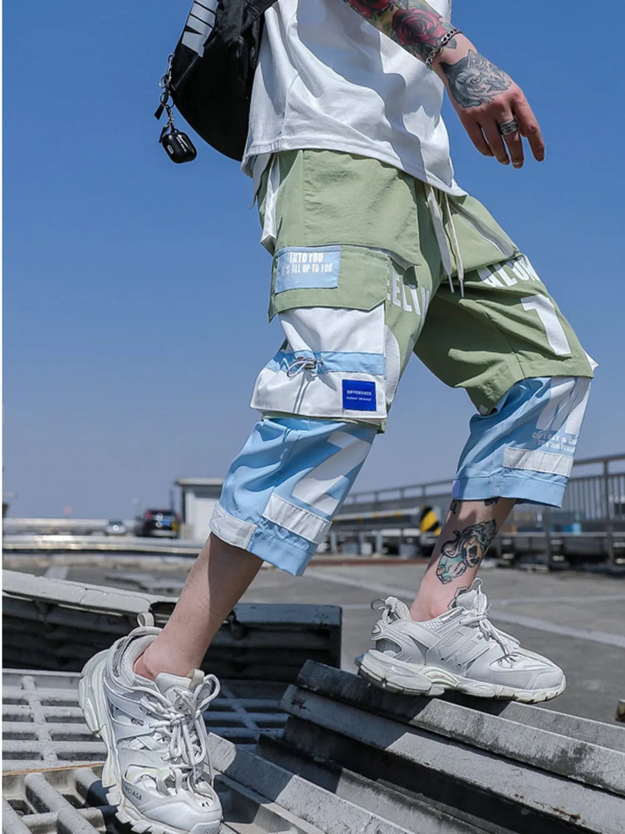 Color block utility cargo pants in light green and light blue with multiple pockets and graphic details.