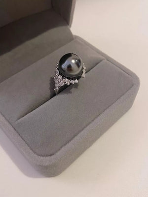Luminous gray pearl and silver ring with sparkling accent stones in a jewelry box.