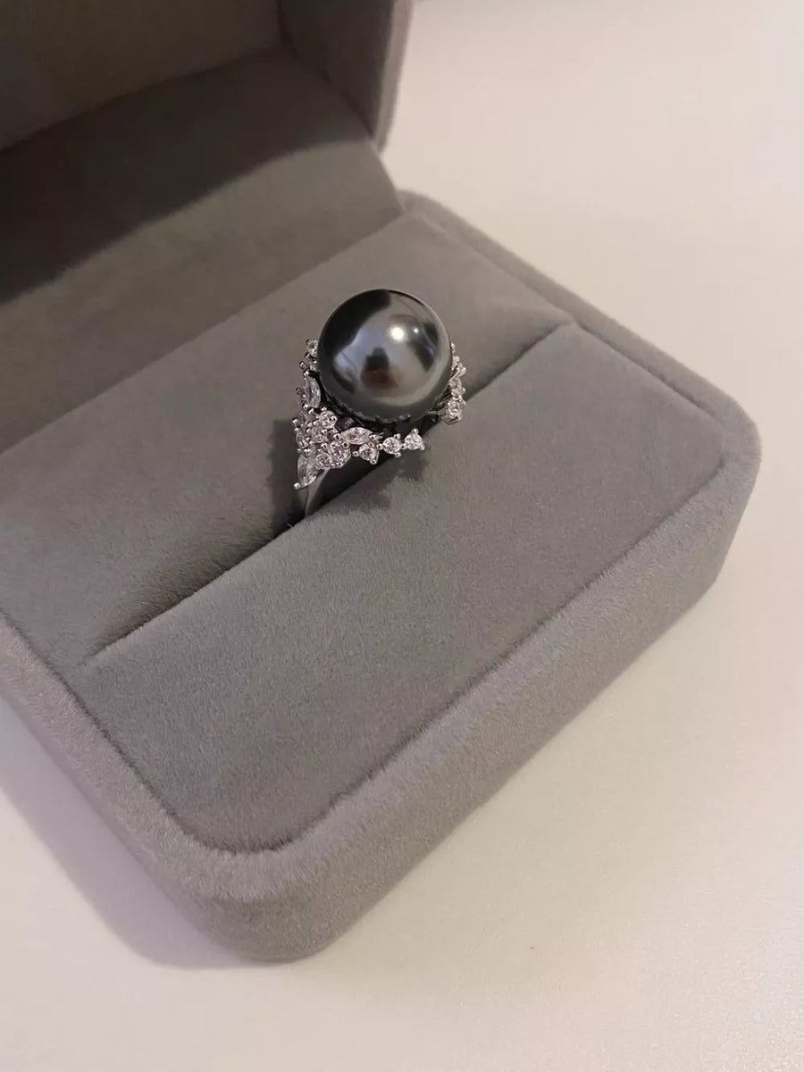 Luminous gray pearl and silver ring with sparkling accent stones in a jewelry box.