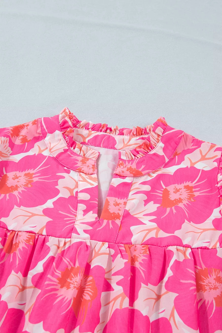 Vibrant floral print polyester blouse with ruffled V-neck and bubble sleeves.
