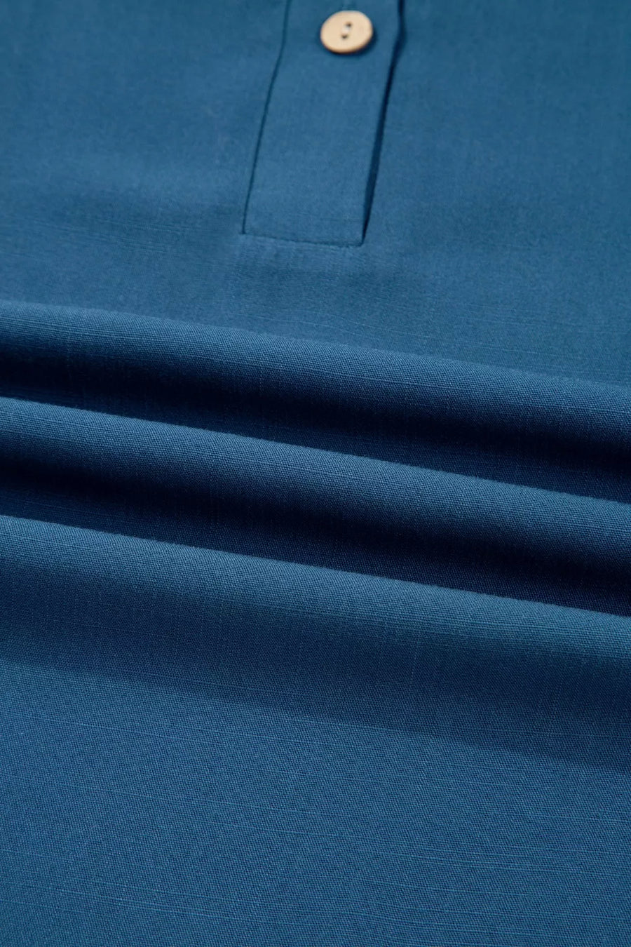 Teal blue linen blend polo shirt with two buttons and a collar.