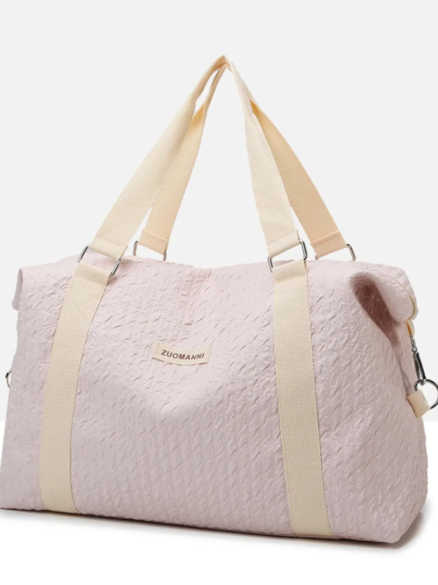 Blush pink waffle-weave weekend bag with cream straps and silver hardware.