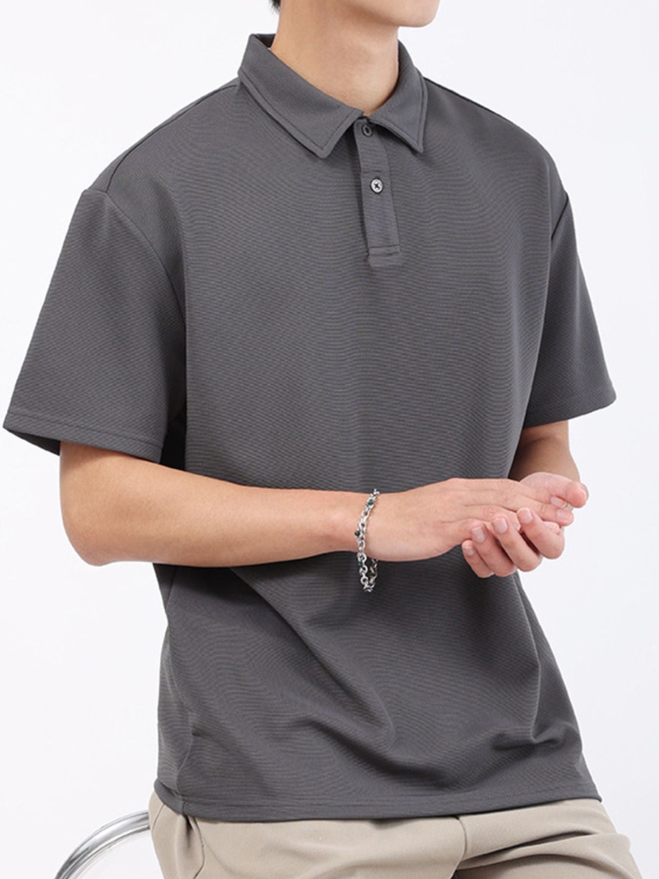Dark gray textured performance polo shirt with short sleeves and a classic collar.