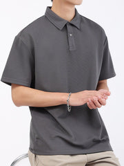 Dark gray textured performance polo shirt with short sleeves and a classic collar.