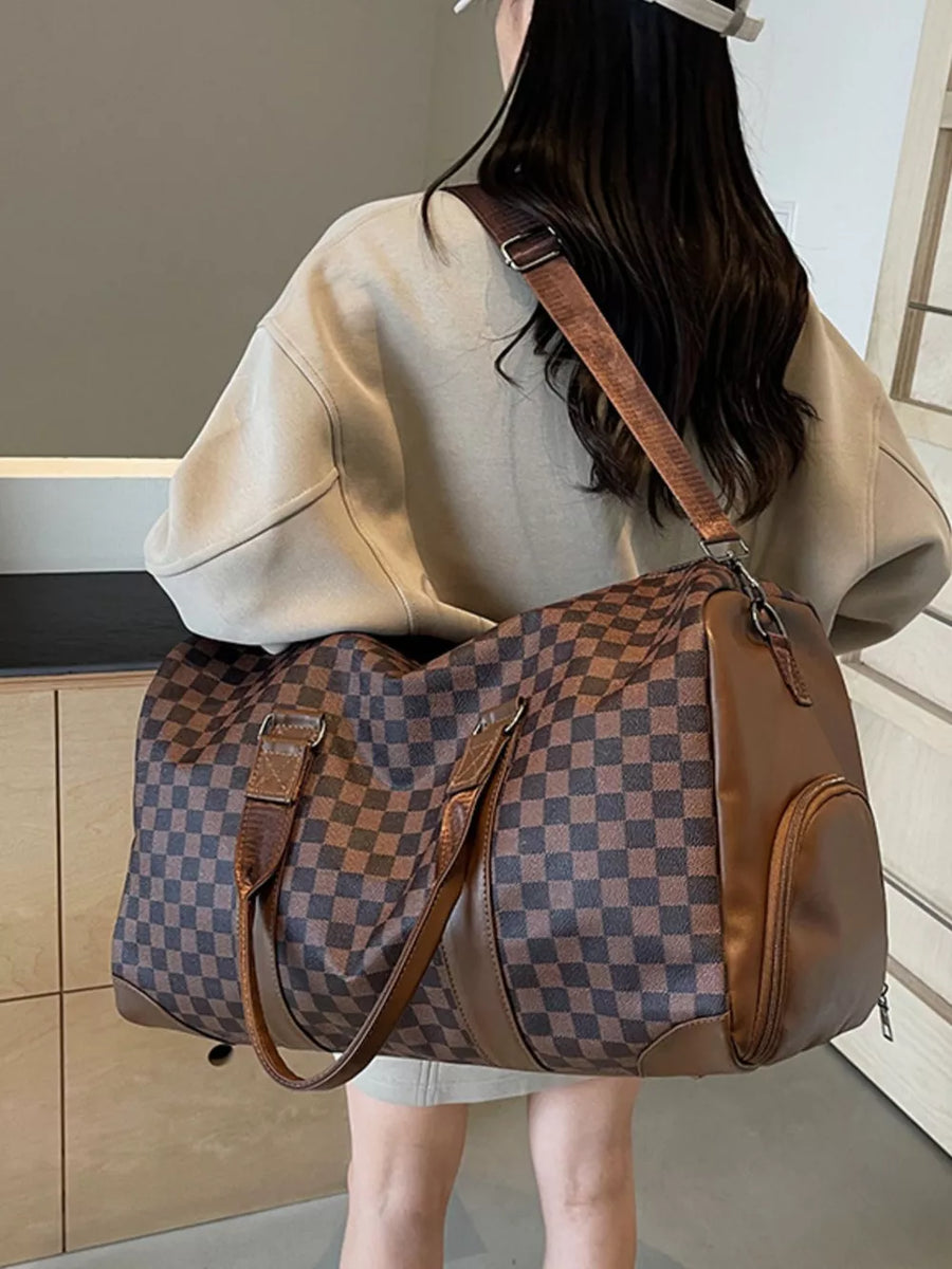 Chic checkered travel bag with brown leather accents and adjustable strap.