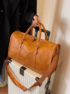 Cognac vintage leather duffle bag with top handles and crossbody strap on luggage.