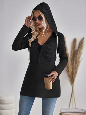 Black cable-knit hooded zip jacket with white drawstrings and contrast textured bodice.