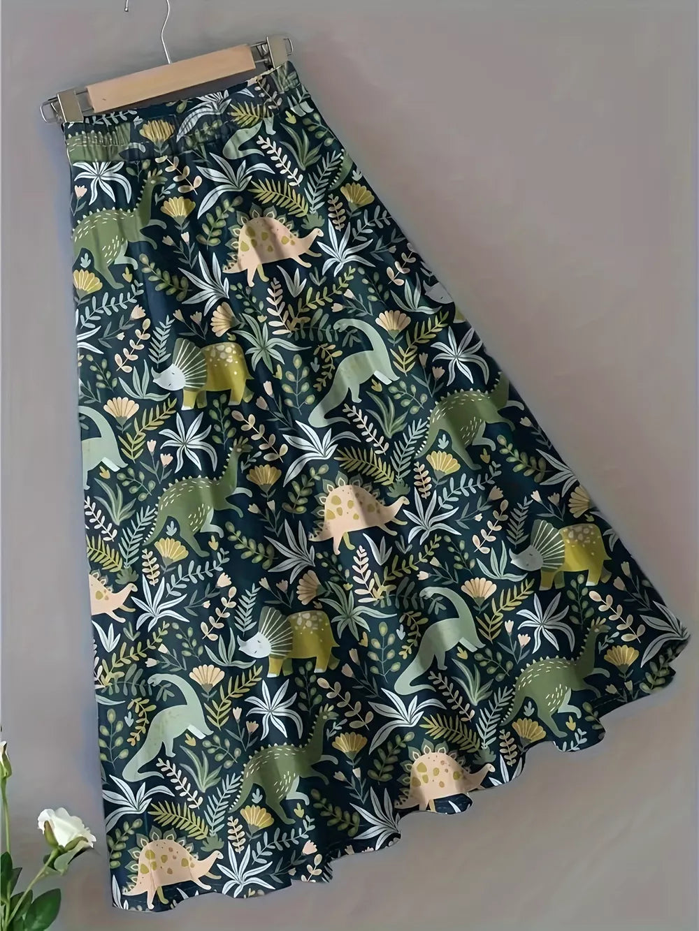 A-line skirt with elastic waist and dinosaur print in dark green with botanical accents.