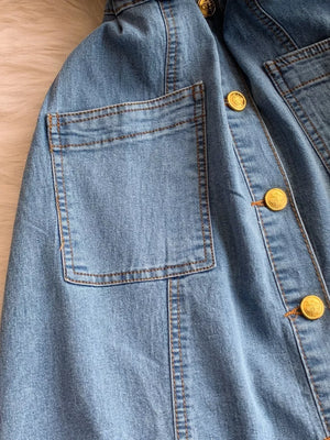 Light blue denim dress with buttoned front, chest pocket, and gold buttons.