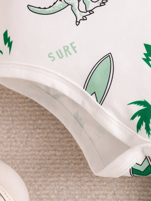 Baby bodysuit with dinosaur, surfboard, and palm tree print.