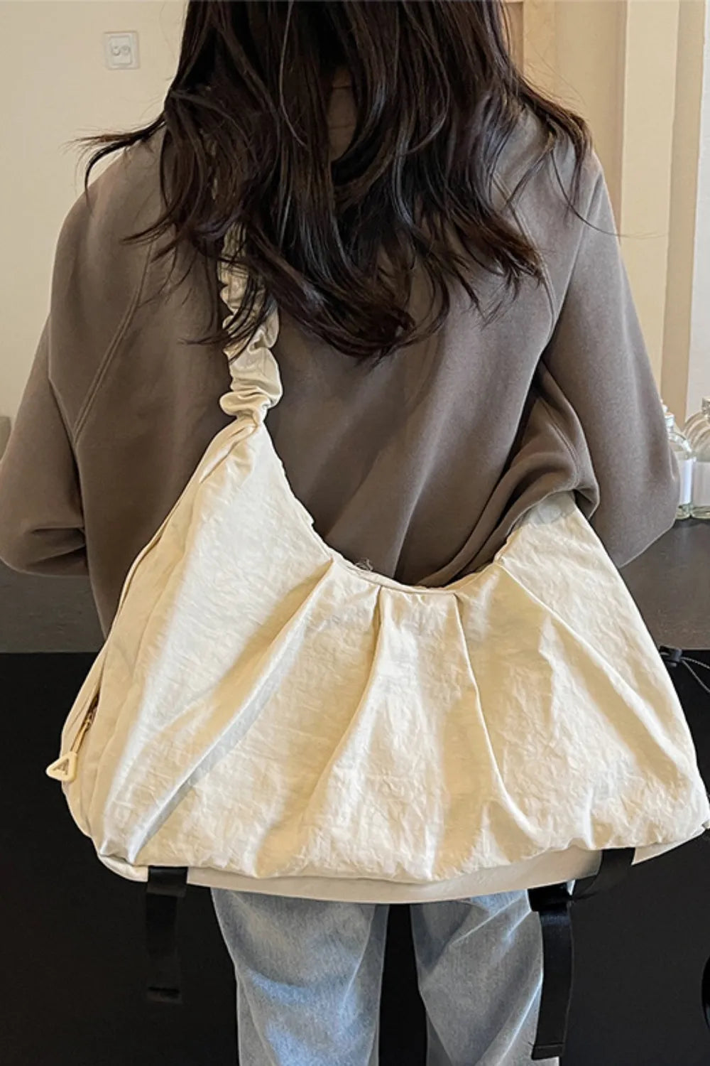 Gathered crescent shoulder bag in beige with ruched strap detail and gathered front.