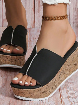 Black cork platform slides with zipper detail and white-tipped toes.