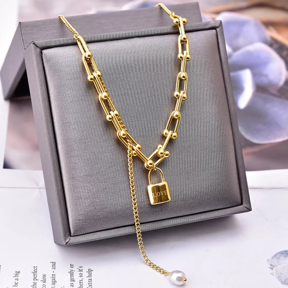necklace in gold featuring lock pendant and draped fit