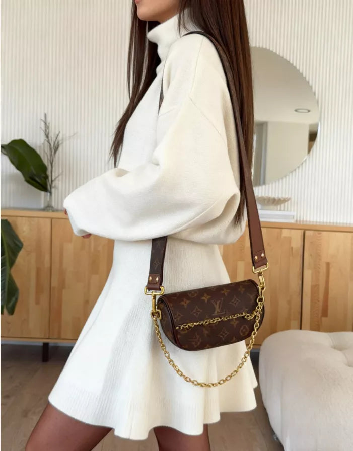 White turtleneck sweater and flared skirt set with a brown monogram crossbody bag.