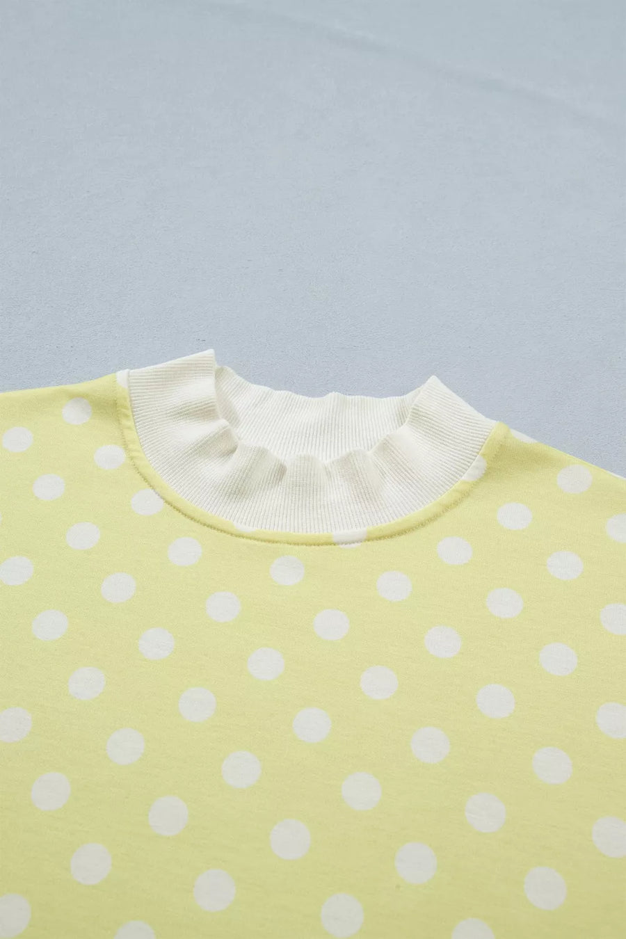 Pastel yellow polka dot top with ruffled neckline detail