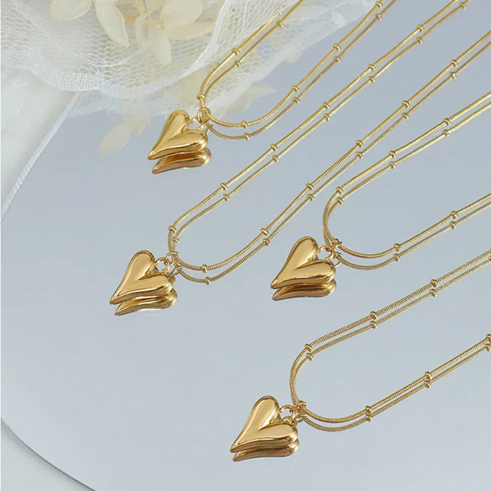Gold necklaces with sculpted heart pendants and beaded chains.