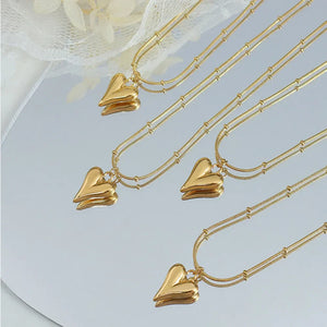 Gold necklaces with sculpted heart pendants and beaded chains.