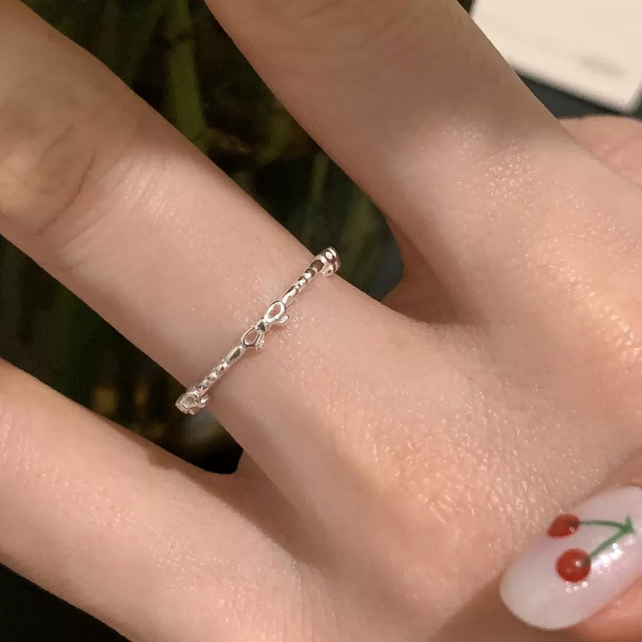 Delicate sterling silver ring with a dainty bow pattern.