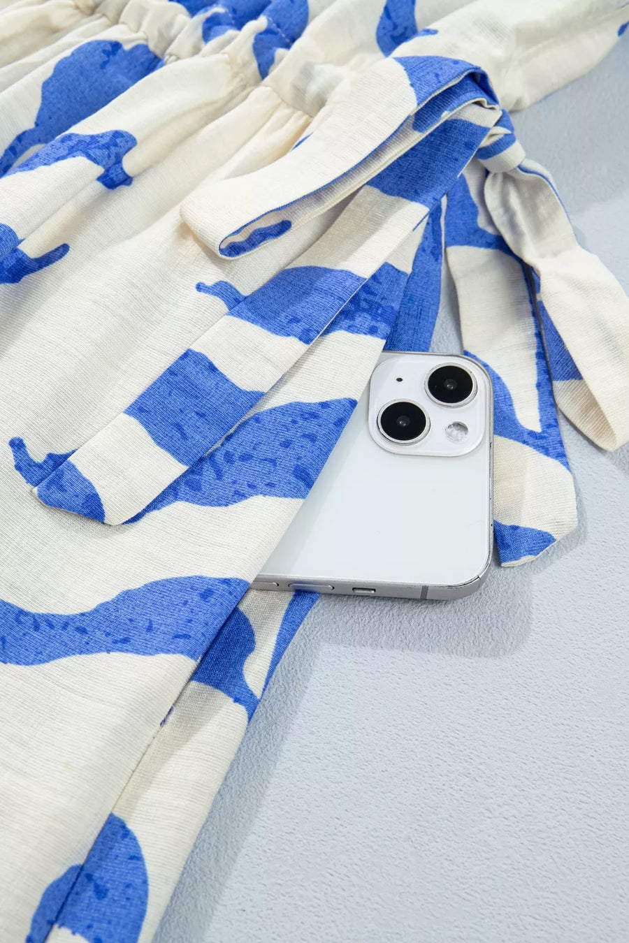 Botanical print maxi dress with side tie detail and a white phone tucked into the waist.
