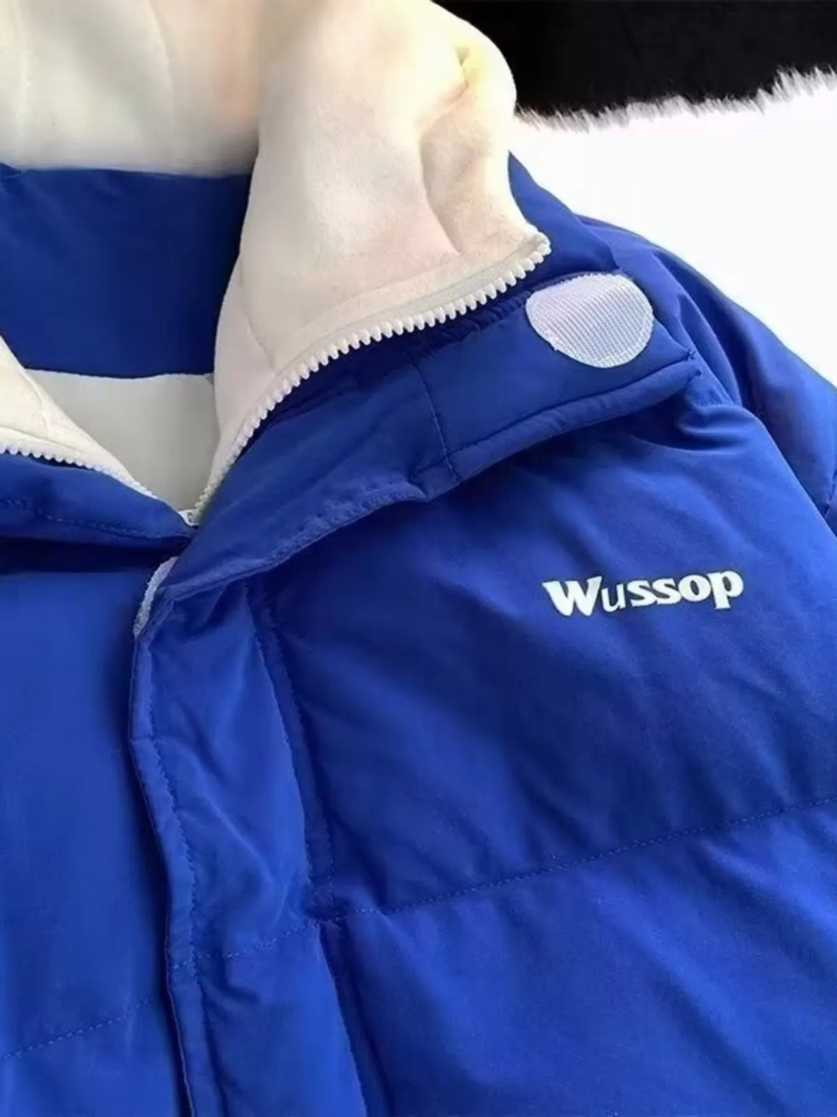 Men's blue quilted puffer jacket with white collar and "Wussop" logo detail.