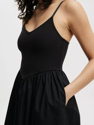 Black midi dress with V-neck, ribbed bodice, and full skirt with pockets.
