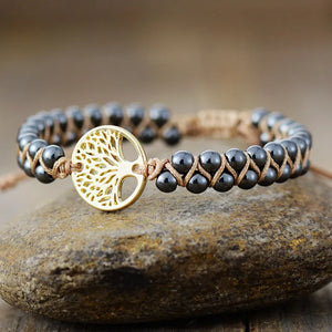 Gold Tree of Life braided bead bracelet with dark gray beads on tan cord.