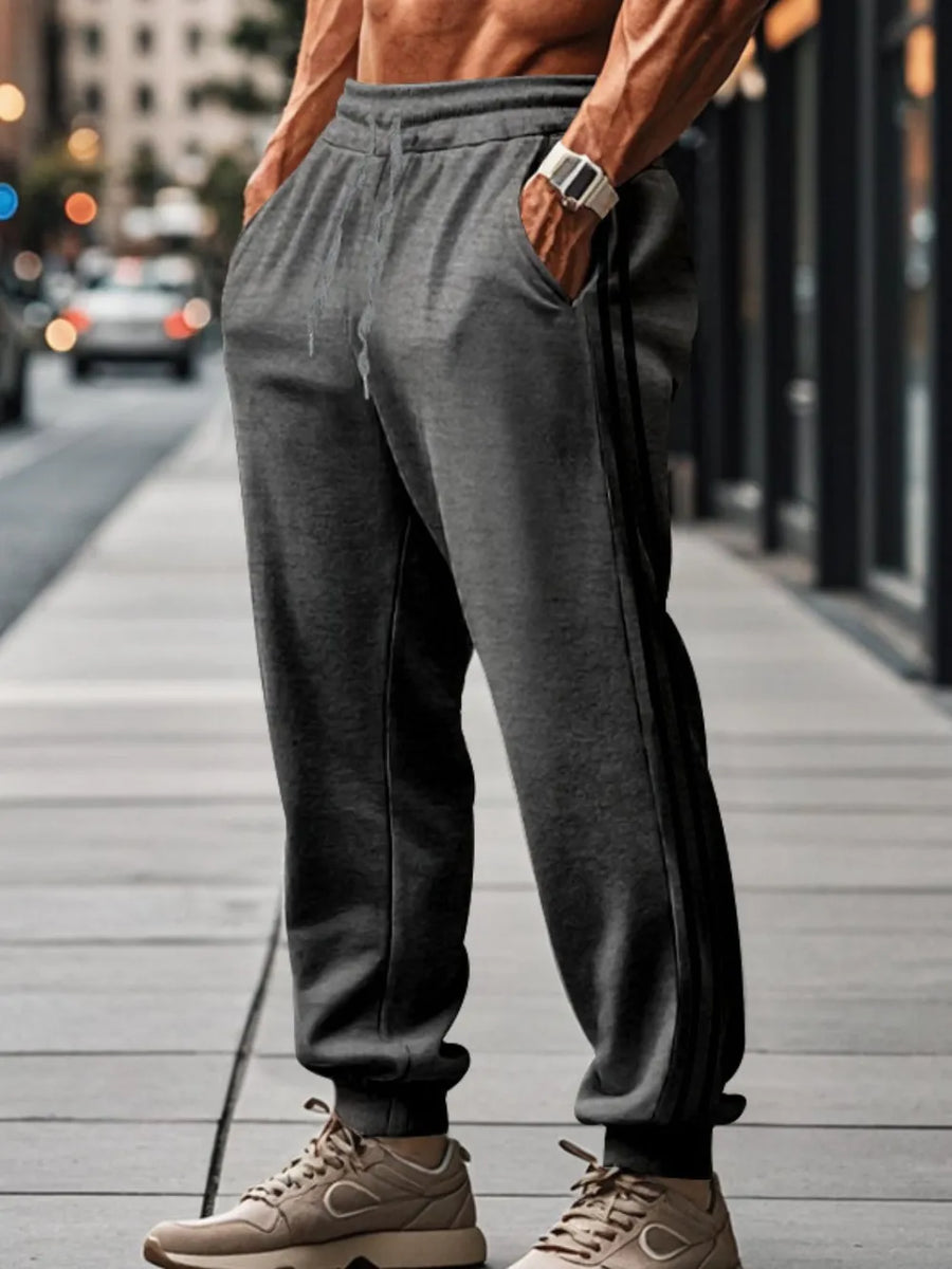 Gray athletic joggers with black side stripes, drawstring waist, and cuffed ankles.
