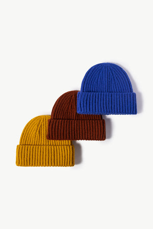 Chunky ribbed knit beanies in yellow, brown, and blue.