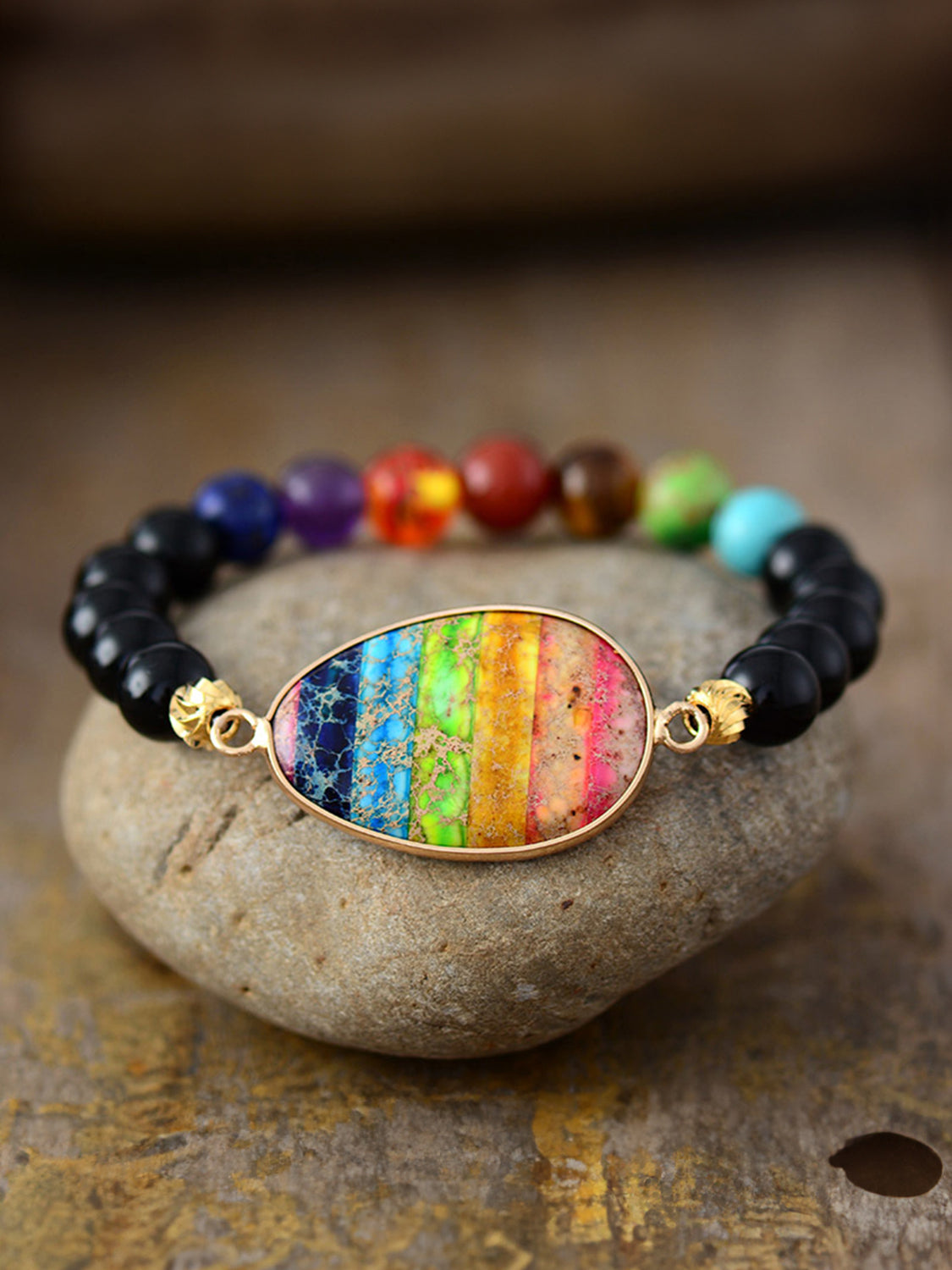 Prismatic bead and stone bracelet with multicolor striped pendant and black beads.
