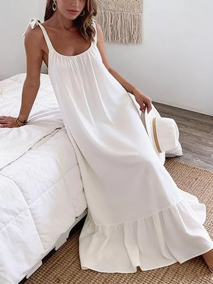White maxi dress with tie straps, scoop neck, and ruffled hem.