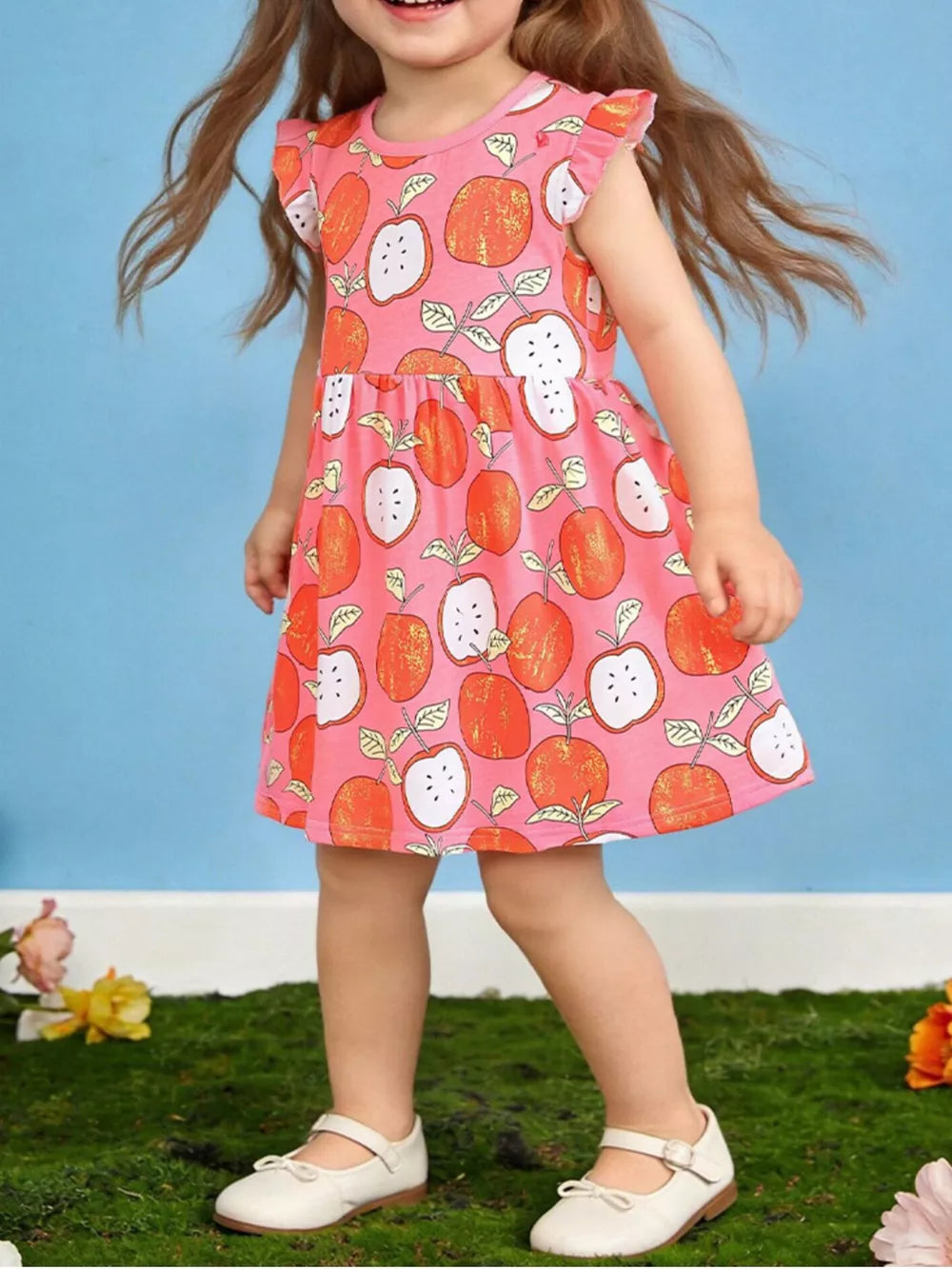 Baby dress with playful apple print, ruffle sleeves, and cotton fabric.