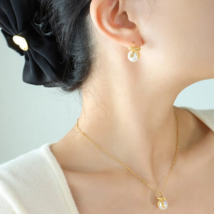 Gold bow-adorned pearl drop necklace with delicate bead chain.