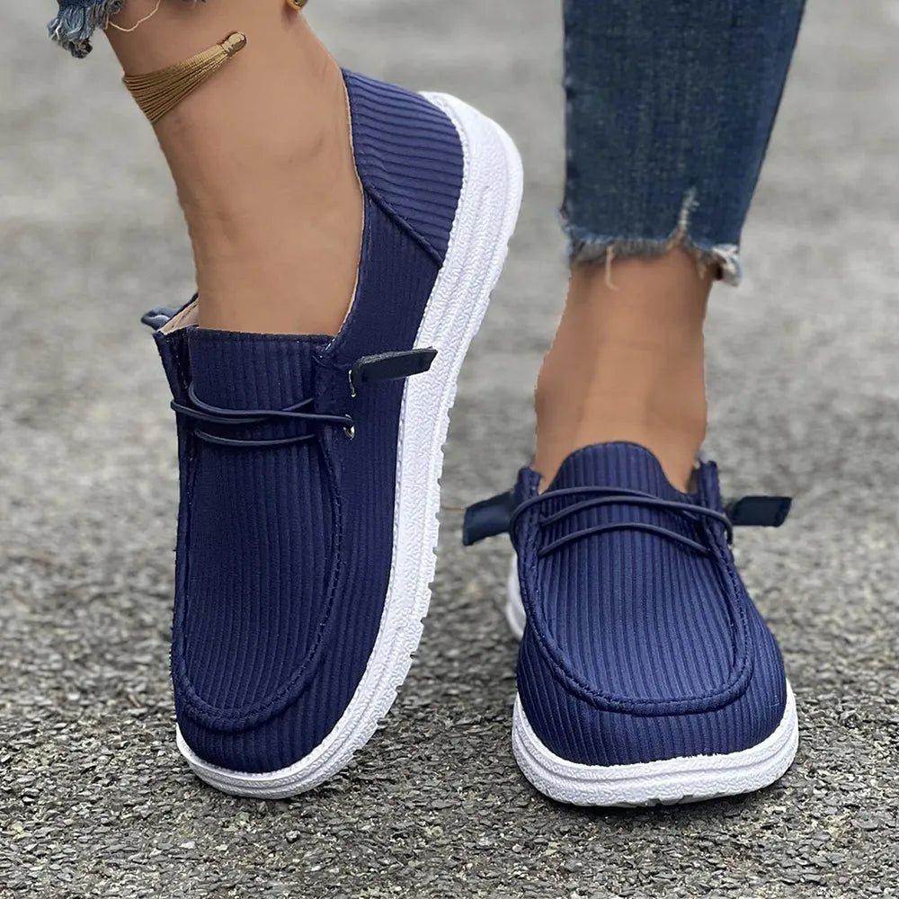 Navy corduroy boat shoes with white soles and lace detail.