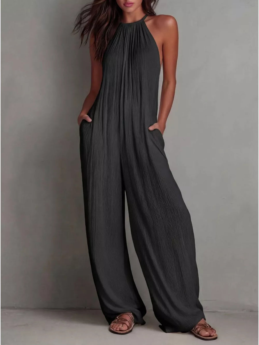 Black wide-leg jumpsuit with halter neck and pockets, textured fabric.