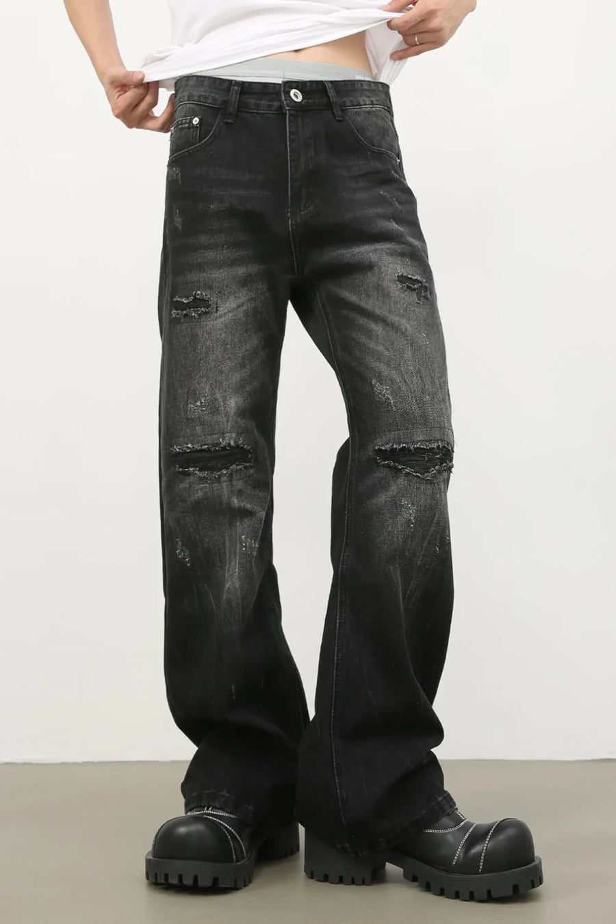 Distressed dark wash flare jeans with bleach details and ripped knees.