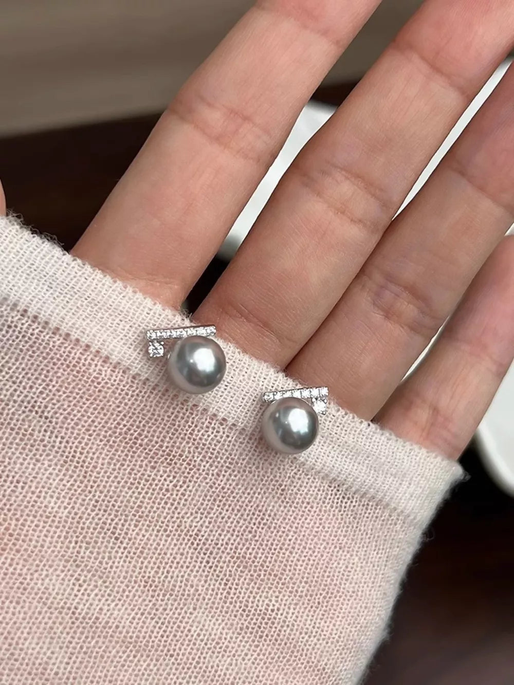 Zircon pearl stud earrings with diamond accents in light gray.
